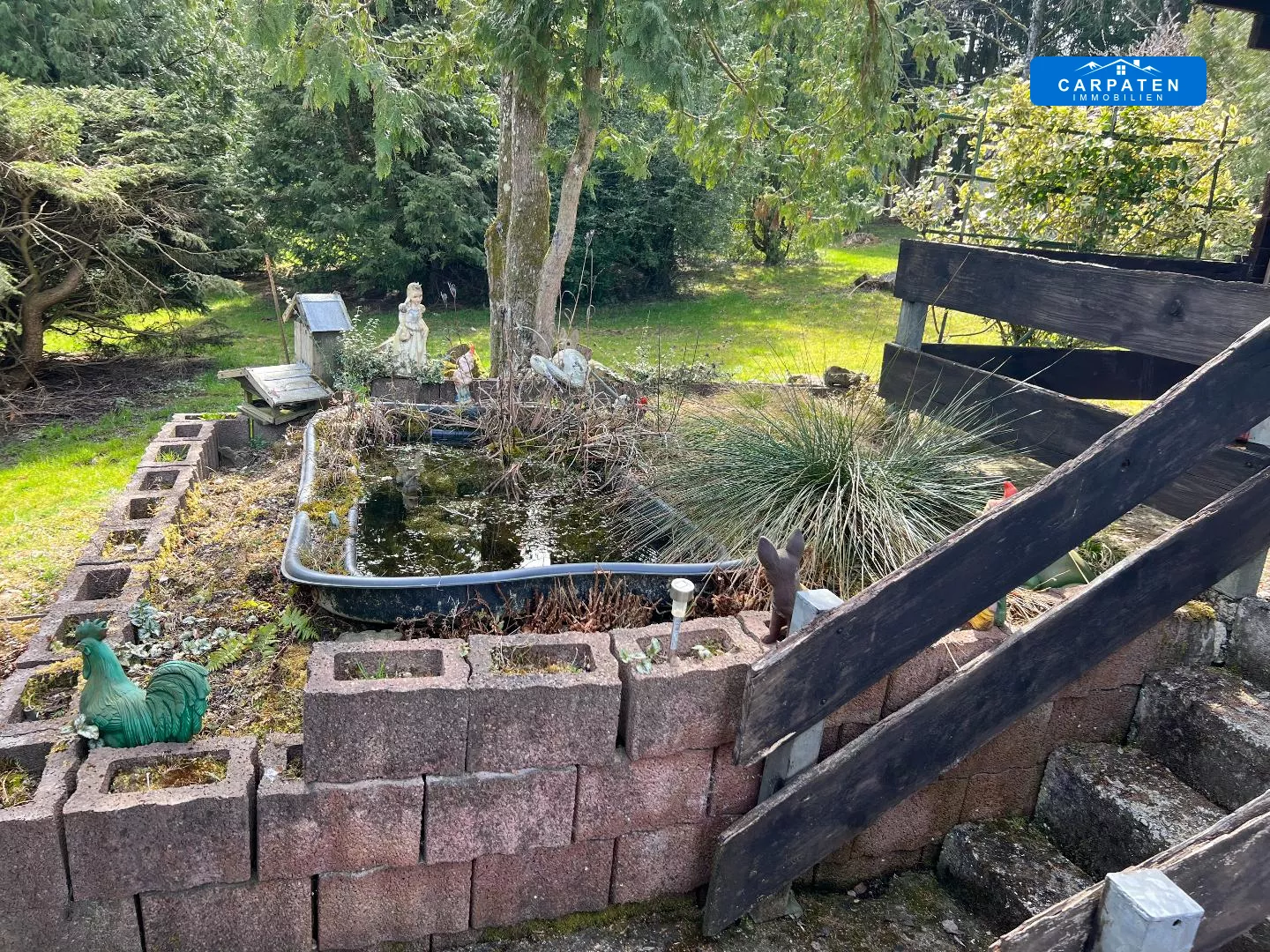 Gartenteich mit Figuren und Holztreppe
